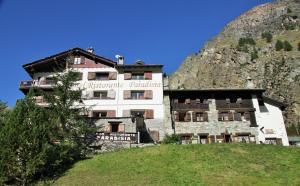 een gebouw op een heuvel voor een berg bij Hotel Paradisia in Cogne