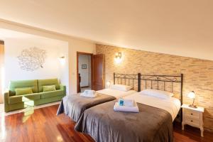 ItziarにあるCasa Rural Zelaieta BerriBiのベッド2台と緑のソファが備わるホテルルームです。