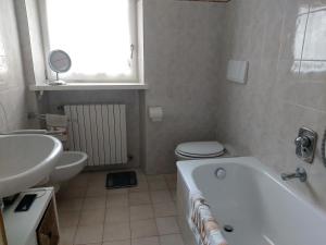 ein Badezimmer mit einer Badewanne, einem WC und einem Waschbecken in der Unterkunft APPARTAMENTO CORTINA 1956 in Cortina d'Ampezzo
