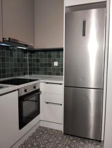 La cuisine est équipée d'un réfrigérateur en acier inoxydable et de placards blancs. dans l'établissement Juliet IsimeriaHomz, à Thessalonique
