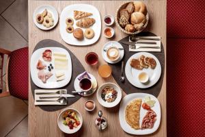 a wooden table with plates of breakfast food on it at Hotel Chalet Sas Morin in Pozza di Fassa