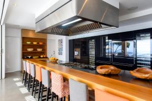 a kitchen with a long counter with orange chairs at Sa Caleta Hill in Sant Josep