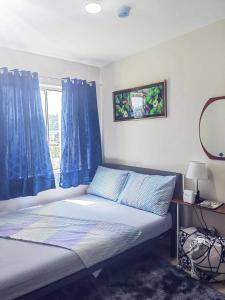 1 dormitorio con 1 cama con cortinas azules y ventana en 8 spatial condo near downtown, coffee shop, SNR, Sm, hospital, Schools 2b fully furnished, en Davao City