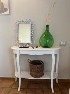 a white console table with a mirror and a vase at Masseria Santacatrini in Melilli