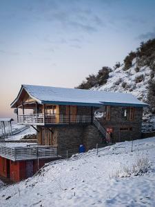 dom na szczycie pokrytego śniegiem wzgórza w obiekcie Griffons Cafe and Stay w mieście Dharamsala