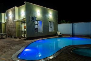 a swimming pool in front of a house at night at Nyamfinzi Hotel in Chipata