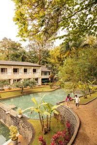 two people standing near a pond in a park at Hotel Mercedes in Ilhabela