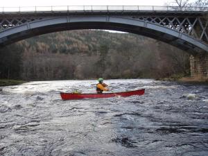 a person in a red canoe on a river under a bridge at Ben View Aberlour Luxury Barn Conversion in Aberlour