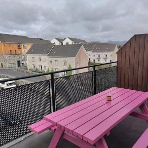 a pink picnic bench sitting on a balcony with a city at Apt 3 The Grainstore in Clifden