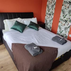 a bed with green pillows and towels on it at Apt 3 The Grainstore in Clifden