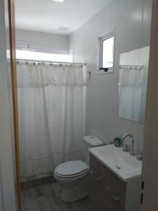 a white bathroom with a toilet and a sink at Aires de la costa Renovado in Neuquén