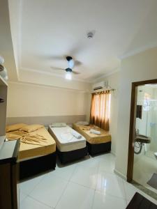 a room with three beds and a window at Basilica Palace Hotel in Aparecida