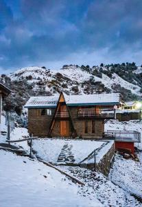 une maison recouverte de neige devant une montagne dans l'établissement Griffons Cafe and Stay, à Dharamshala