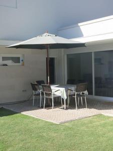 a table and chairs with an umbrella on a patio at Sea wave sounds, Meco, by the beach in Sesimbra