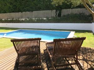 two chairs sitting on a deck next to a swimming pool at Sea wave sounds, Meco, by the beach in Sesimbra