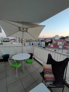 einen Balkon mit einem Tisch, Stühlen und einem Sonnenschirm in der Unterkunft Terrasse - Studio Californie in Cannes