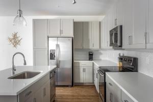 uma cozinha com armários brancos e um frigorífico de aço inoxidável em Kasa Greenville Dallas em Dallas