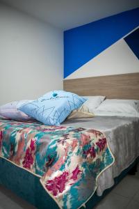 a bed with a colorful comforter and a pillow at Hotel Santo Tomas Bogota in Bogotá