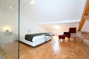a bedroom with a bed and a red chair at Apartamentos Premium Familiares - Loft Guesthouse BeMyGuest Viseu in Viseu
