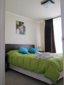 1 dormitorio con 1 cama con sábanas verdes y almohadas azules en Santiago Central Suites, en Santiago