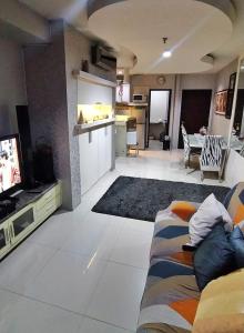 a living room with a couch and a tv and a kitchen at Cosmo mansion apartment in Jakarta