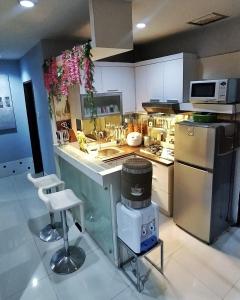eine Küche mit einem Herd und einer Theke mit Hockern in der Unterkunft Cosmo mansion apartment in Jakarta