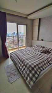 ein Schlafzimmer mit einem Bett und einem großen Fenster in der Unterkunft Cosmo mansion apartment in Jakarta