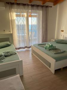 two beds sitting in a room with a window at Wave n' Sea Apartments in Himare