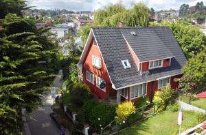 a red house with a black roof at La Guapa Hostel in Puerto Varas