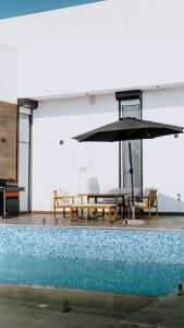 een zwembad met een tafel en een parasol bij Hummingbird Rak in Ras al Khaimah