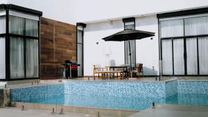 a swimming pool with a table and an umbrella at Hummingbird Rak in Ras al Khaimah