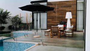拉斯海瑪的住宿－Hummingbird Rak，一个带桌子和遮阳伞的庭院,毗邻一个游泳池