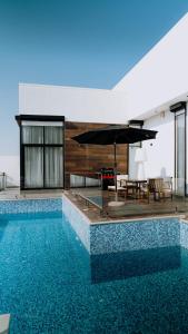 a swimming pool with a table and an umbrella at Hummingbird Rak in Ras al Khaimah