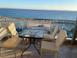 una mesa y sillas en un balcón con vistas al océano en Wave n' Sea Apartments en Himare