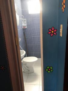 a bathroom with a toilet and a bathroom with flowers on the door at Baleia Beach - Casa de Praia in Itapipoca