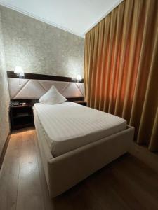 a small bedroom with a bed and a curtain at Diar in Atyrau +1 photo