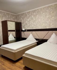 a bedroom with two beds and a mirror at Diar in Atyraū