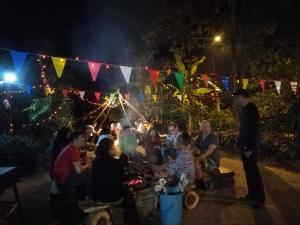 un gruppo di persone sedute ad una festa di notte di Crossroads house a Mae Hong Son