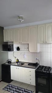 cocina con armarios blancos y estufa negra en Confortável, Equipado e Bem Localizado c/ Garagem, en Curitiba