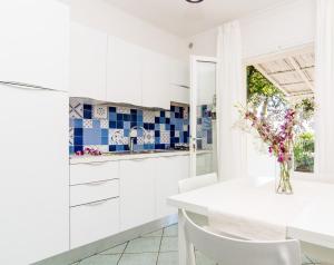 uma cozinha com armários brancos e um vaso de flores em Colibrì by SolturElba em Capoliveri