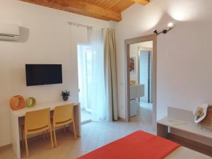 ein Wohnzimmer mit einem Tisch, Stühlen und einem TV in der Unterkunft Alcamo Rooms con garage privato in Alcamo