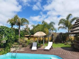 una piscina con 2 tumbonas y una sombrilla en La casa ideal para el momento que buscabas., en Punta del Este