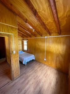 a room with a bed in a wooden cabin at Cabaña la percha in Coihaique