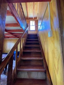 a staircase in a house with wooden walls and wooden floors at Cabaña la percha in Coihaique