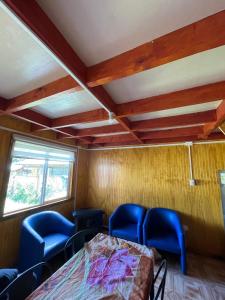 a room with blue chairs and a bed in it at Cabaña la percha in Coihaique