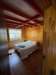 a bedroom with a bed in a wooden room at Cabaña la percha in Coihaique