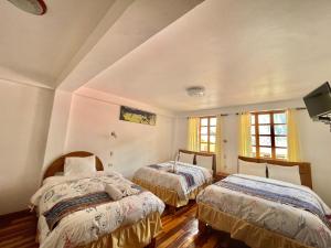 a bedroom with two beds and two windows at Intitambo Hotel in Ollantaytambo