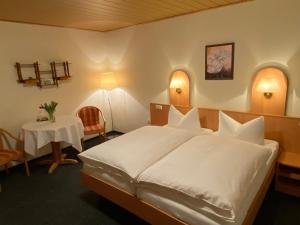 a bedroom with a large white bed and a table at Pension Haufe in Ohorn