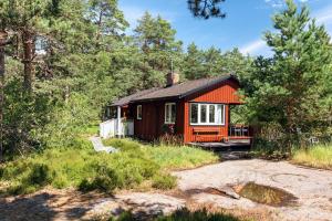 uma pequena cabana vermelha na floresta com árvores em Authentic Swedish family home on the archipelago em Stavsnäs
