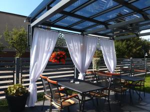 a pergola with tables and chairs under it at Pokoje Sandra I in Łeba